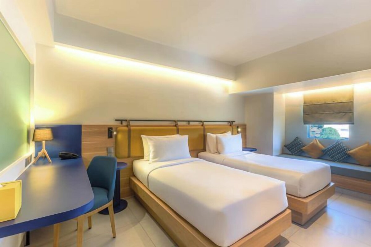 Ein Hotelzimmer mit zwei Betten, einem Schreibtisch und einem Stuhl.