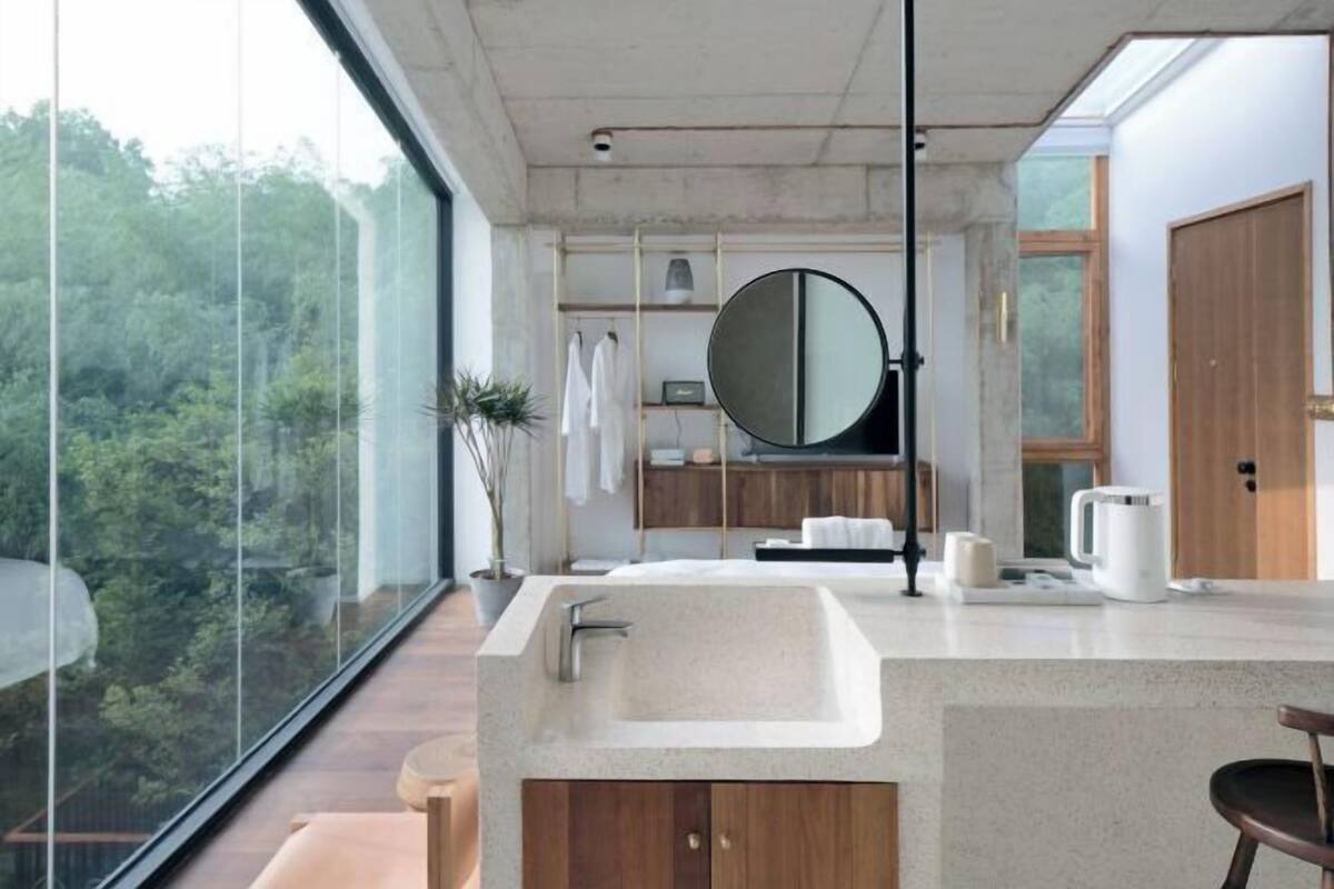 A modern bathroom with a large window, a round mirror, and a sink.