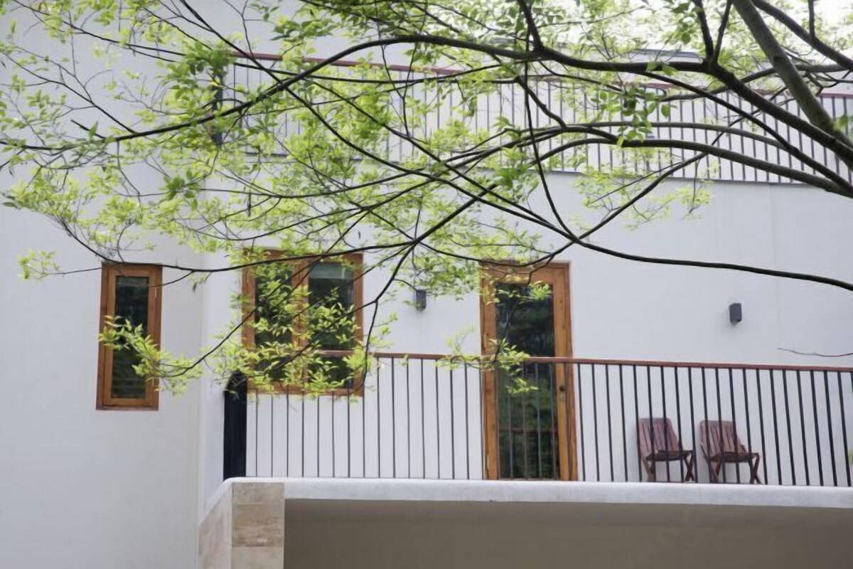 A white building with a balcony, two windows, and a metal railing.