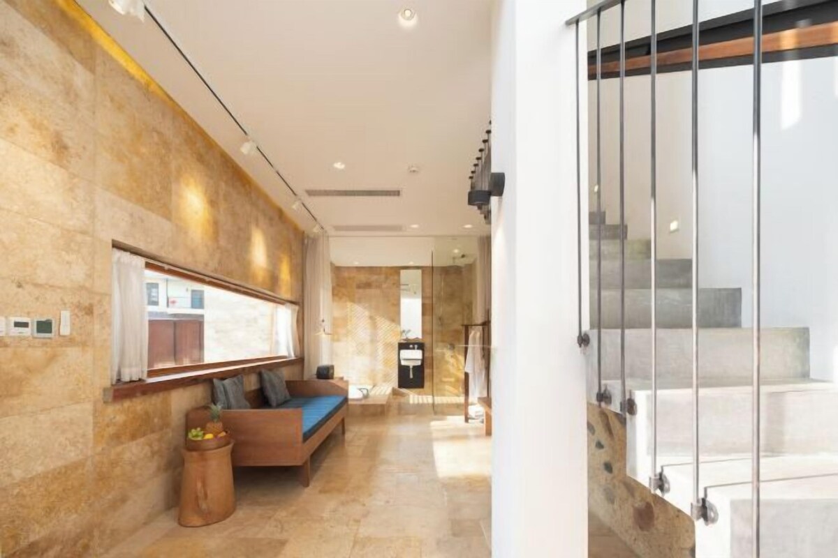 A modern lobby with a stone wall, a seating area, and a staircase.