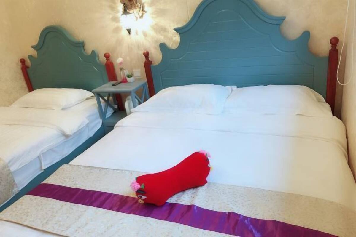 A hotel room with two beds, a nightstand, and a wall-mounted light fixture.
