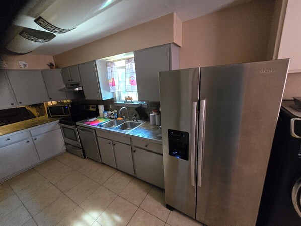 A modern kitchen with stainless steel appliances, including a refrigerator and a microwave. - Five Full Appointed Bedroom House in Quiet Neighborhood (Baker)