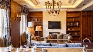 A living room with a sofa, a coffee table, a TV, and a chandelier. - Rongchen International Holiday Hotel (Zhangjiakou)