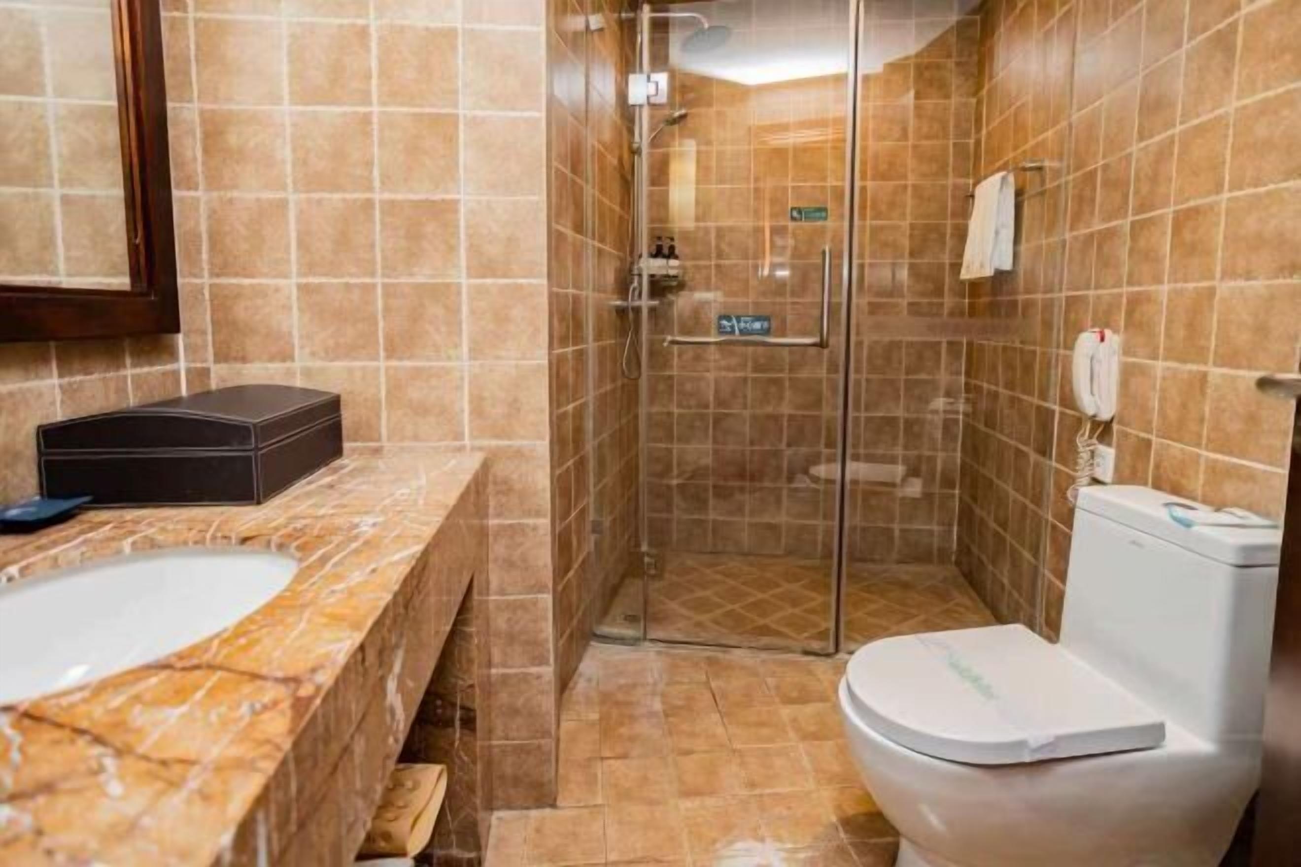 A bathroom with a marble sink, a toilet, and a glass-enclosed shower.