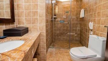 A bathroom with a marble sink, a toilet, and a glass-enclosed shower.