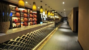 A hotel lobby with a long reception desk, multiple pendant lights, and a patterned wall. - Rongchen International Holiday Hotel (Zhangjiakou)