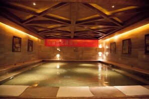A large indoor swimming pool with a wooden ceiling and stone walls. - Rongchen International Holiday Hotel (Zhangjiakou)