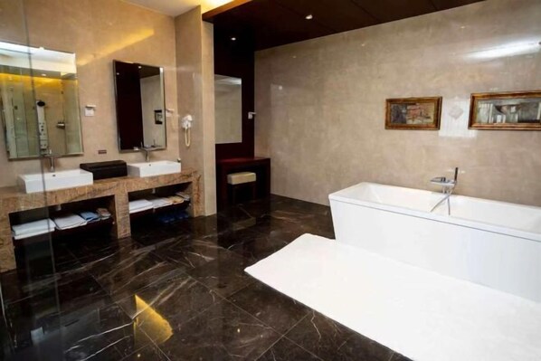 A modern bathroom with a large bathtub, two sinks, and a vanity with a mirror. - Rongchen International Holiday Hotel (Zhangjiakou)