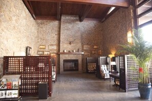 Una habitación con paredes de piedra, chimenea, muebles de madera y una planta en maceta.