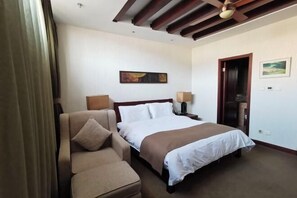 A hotel room with a bed, a sofa, a painting on the wall, and a door. - Rongchen International Holiday Hotel (Zhangjiakou)