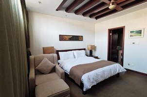 Una habitación de hotel con una cama, un sofá, un cuadro en la pared y una puerta.