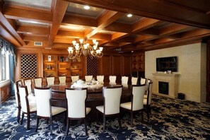 Un comedor formal con una mesa redonda, sillas, una araña y una chimenea.