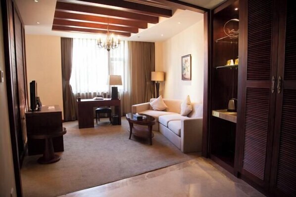 A hotel room with a sofa, a desk, a coffee table, a chandelier, and a wardrobe. - Rongchen International Holiday Hotel (Zhangjiakou)