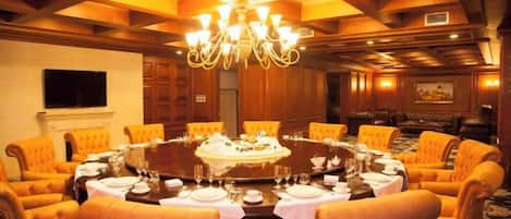 Un salón de conferencias con una mesa redonda, sillas y un candelabro.