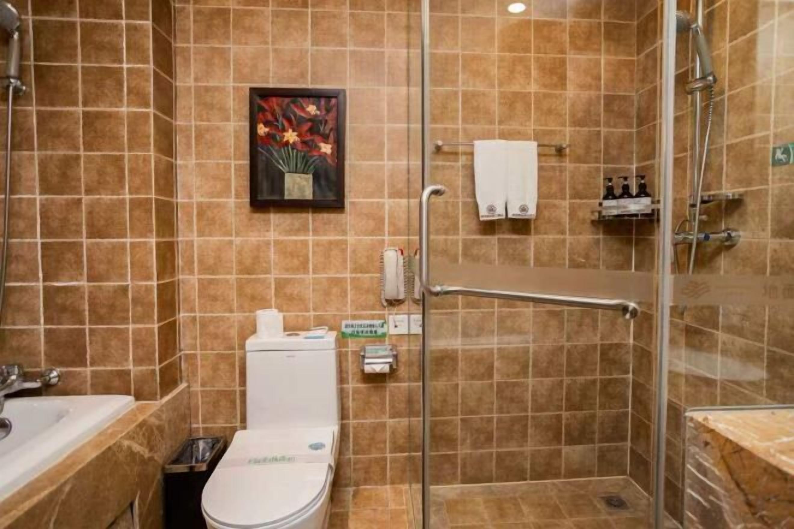 A bathroom with a toilet, shower, and a glass-enclosed shower stall.