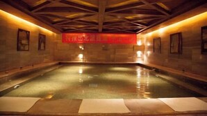 A large indoor swimming pool with a wooden ceiling and stone walls. - Rongchen International Holiday Hotel (Zhangjiakou)