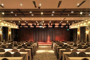 A conference room with rows of tables and chairs, a stage, and a patterned carpet. - Rongchen International Holiday Hotel (Zhangjiakou)