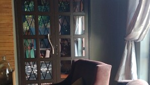 Ein Wohnzimmer mit einem braunen Sofa, einem gemusterten Kissen und einer Holzkabine mit Glastüren.