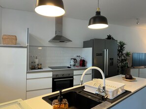 A modern kitchen with a stainless steel refrigerator, a gas stove, and a built-in oven. - Burgães II Apartment (Porto)