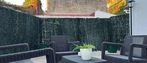 Un área de estar al aire libre con mobiliario de mimbre y una planta en maceta.