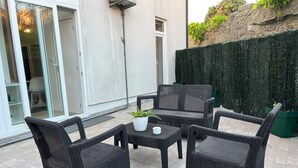 An outdoor patio area with wicker furniture, including a table and four chairs, and a potted plant. - Burgães II Apartment (Porto)