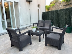An outdoor patio area with wicker furniture, including a table and four chairs, and a potted plant. - Burgães II Apartment (Porto)