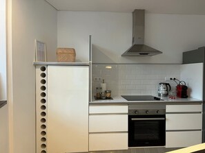 Μια σύγχρονη κουζίνα με εντοιχισμένο φούρνο, εστίες και απορροφητήρα από ανοξείδωτο ατσάλι.