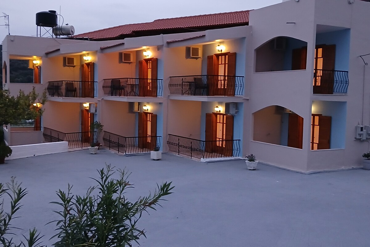 A multi-story building with balconies, outdoor lighting, and a water tank on the roof.