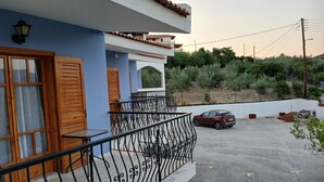 A residential building with a balcony, a car parked in the driveway, and a view of the surrounding greenery. - TOLO BLUE BAY (Nafplio)