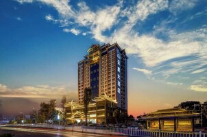 A high-rise hotel with multiple floors, large windows, and a well-lit facade.