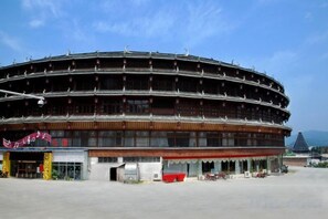 Een groot, rond gebouw met meerdere verdiepingen, vermoedelijk een stadion of arena, met een plat dak en een centrale open ruimte.