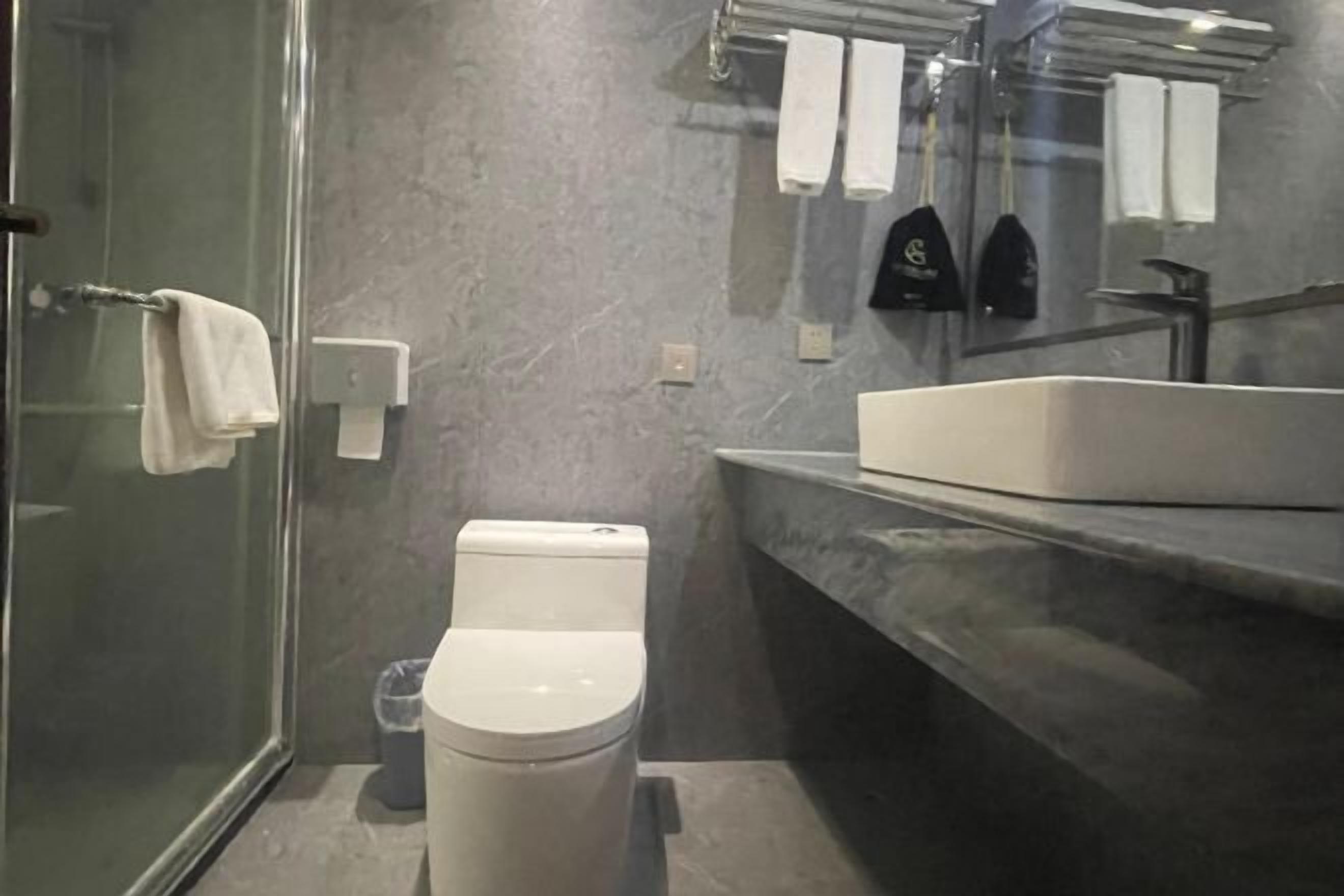 A modern bathroom with a glass shower enclosure, a white toilet, and a large sink with a marble countertop.