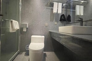 A modern bathroom with a glass shower enclosure, a white toilet, and a large sink with a marble countertop. - Yunding International Hotel (Sanjiang)