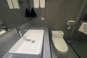 A modern bathroom with a rectangular sink, a toilet, and a glass shower enclosure. - Yunding International Hotel (Sanjiang)