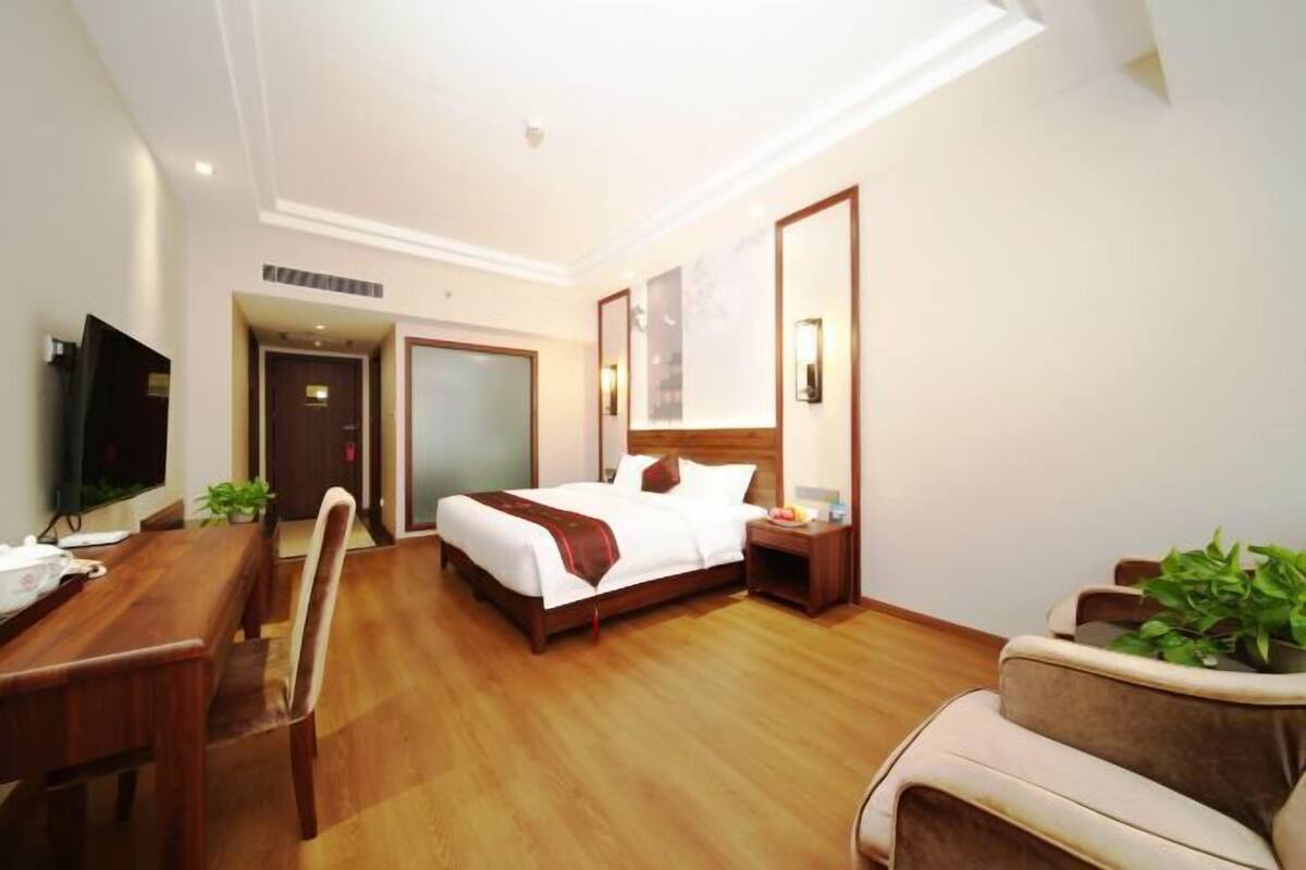 Una habitación de hotel con una cama de madera, un escritorio, una silla y un sofá.