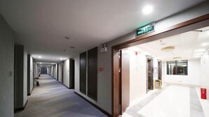 A hotel corridor with a carpeted floor, a wooden door frame, and a sign indicating an exit. - Yunding International Hotel (Sanjiang)