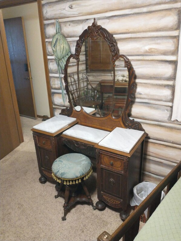 A wooden vanity with a mirror, two drawers, and a stool.
