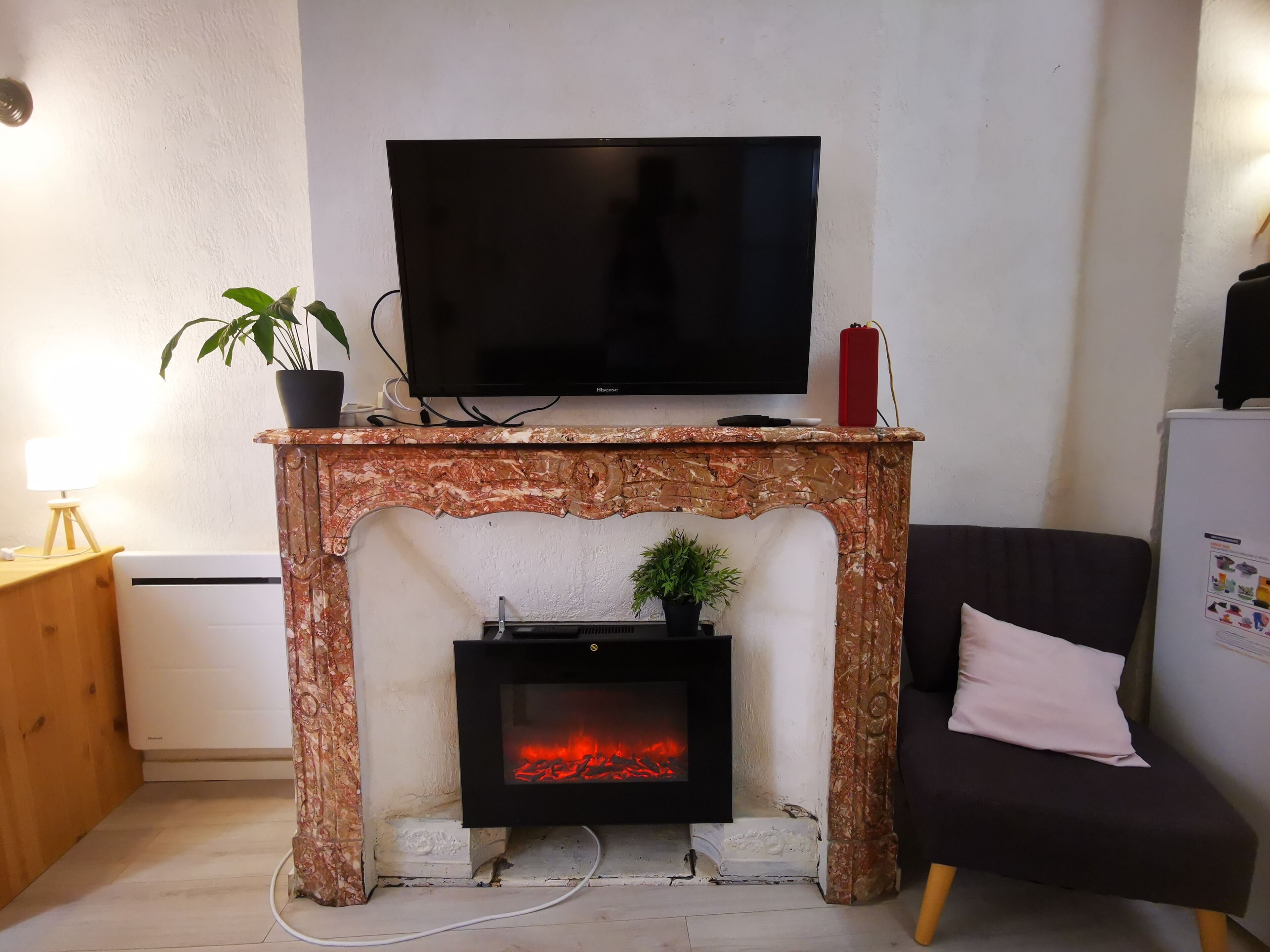 A living room with a fireplace, a television on a mantel, and a sofa.