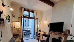 A living room with a sofa, a coffee table, a fireplace, a television, and a balcony with a view.