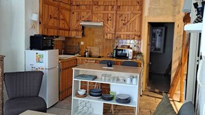 A compact living space with a kitchenette, a sofa, a dining table, and a small TV.