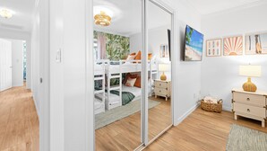 A bedroom with a bunk bed, a bedside table with a lamp, a wall-mounted TV, and framed artwork. - Palm Paradise Retreat - Heated Pool, Spa, Mini Golf (Seminole)