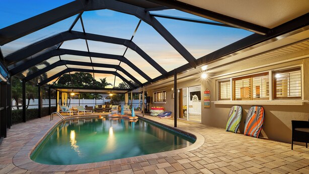 An indoor swimming pool with a glass ceiling, tiled floor, and lounge chairs. - Palm Paradise Retreat - Heated Pool, Spa, Mini Golf (Seminole)