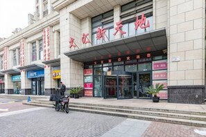 A hotel entrance with a covered entrance, signage, and a person pushing a cart.