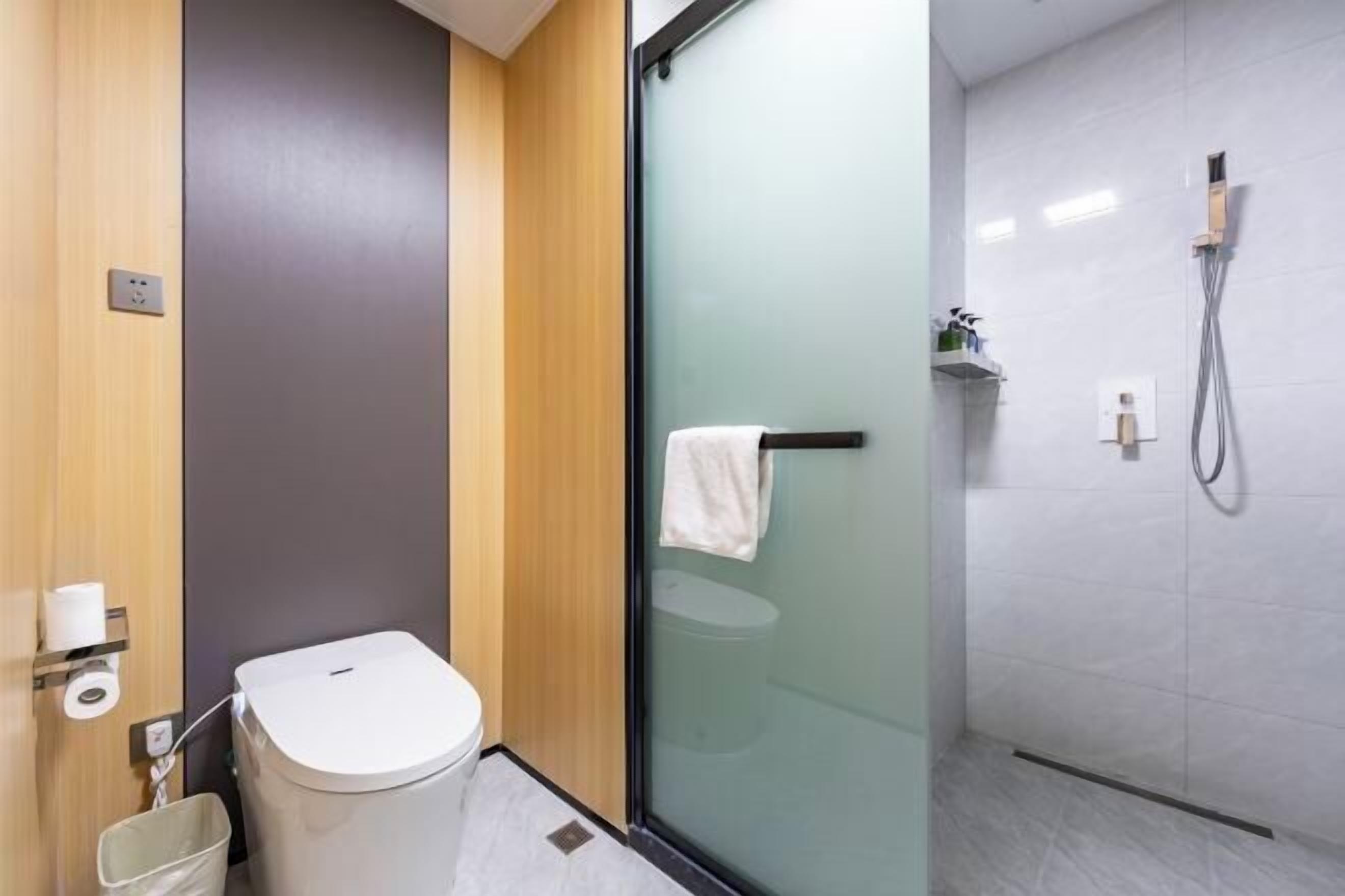 A modern bathroom with a toilet, a glass shower enclosure, and a towel rack.