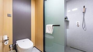 A modern bathroom with a toilet, a glass shower enclosure, and a towel rack.