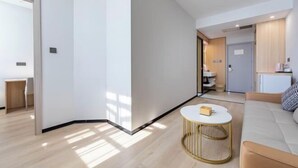 Una sala de estar moderna con un sofá, una mesita de centro y una cocina al fondo.