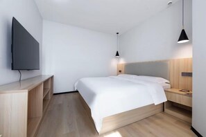 A modern bedroom with a bed, a TV mounted on the wall, a bedside table, and a nightstand. - Wenhui Hotel (Shanghai)