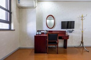 A hotel room with a desk, chair, TV, and a coat stand. - Wenhui Hotel (Shanghai)