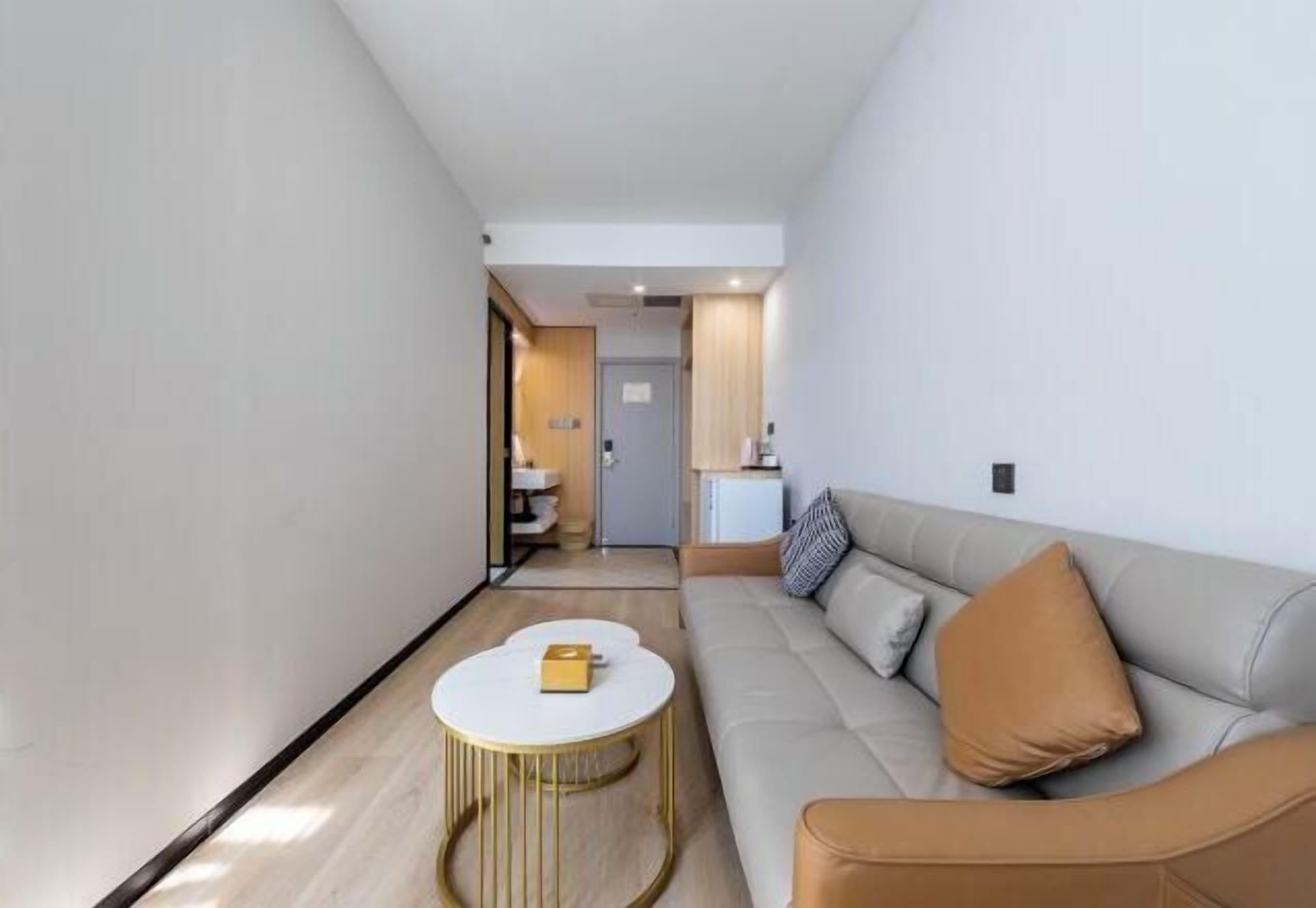 A modern living room with a sofa, a round coffee table, and a view into the kitchen area.