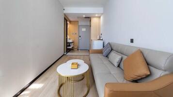 A modern living room with a sofa, a round coffee table, and a view into the kitchen area.